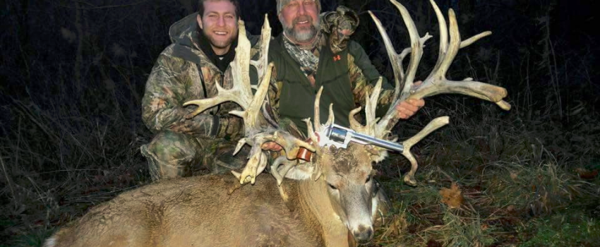 Father and son pose with a potential SCI record buck with a pistol.