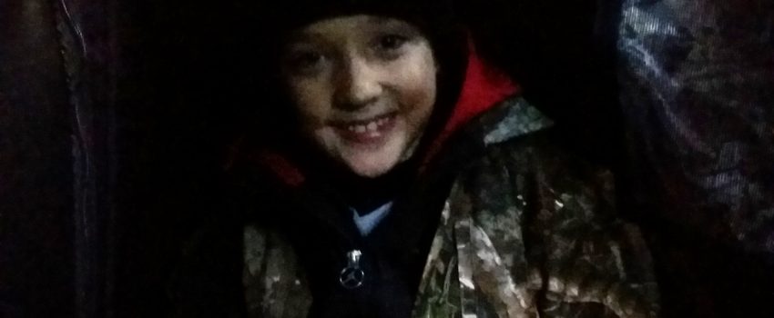 Huddled in the corner of the small blind, Zachery braces against the howling wind on opening day of deer season.